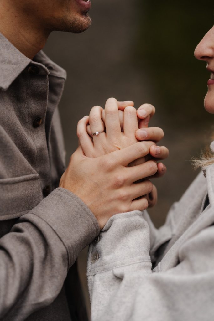 Zwei Personen halten sich liebevoll an den Händen, während sie sich nahe gegenüberstehen.