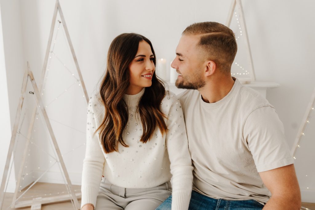 Ein lächelndes Paar blickt sich liebevoll an, umgeben von hellen, minimalistischen Elementen.