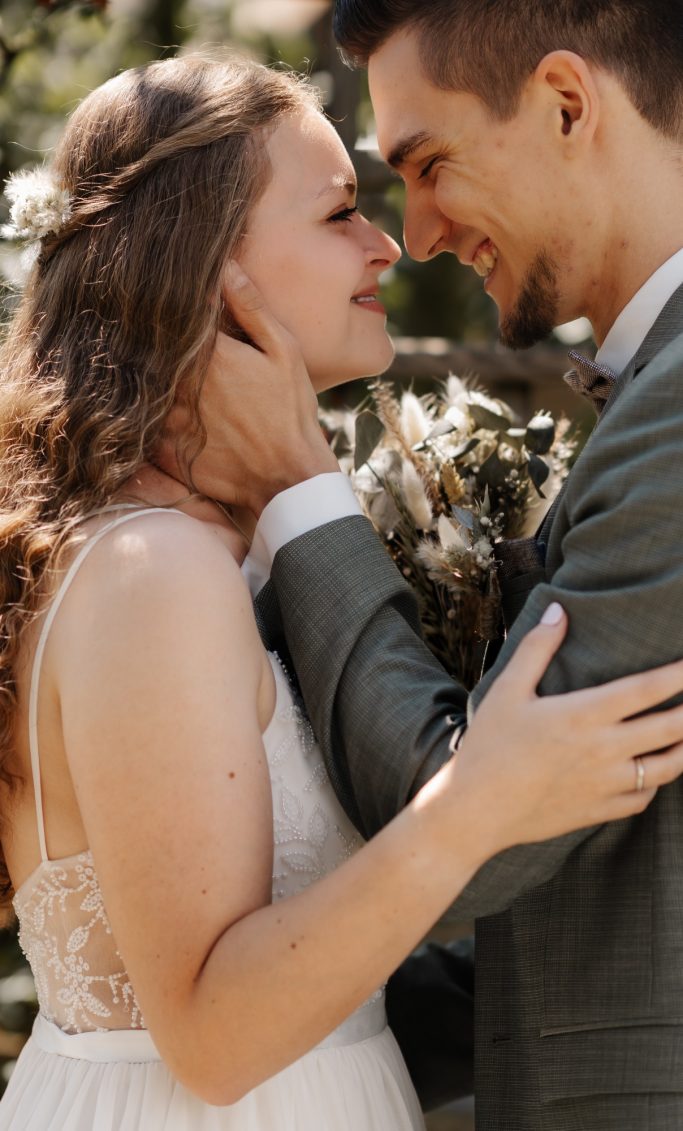 Ein glückliches Brautpaar umarmt sich romantisch im Freien.