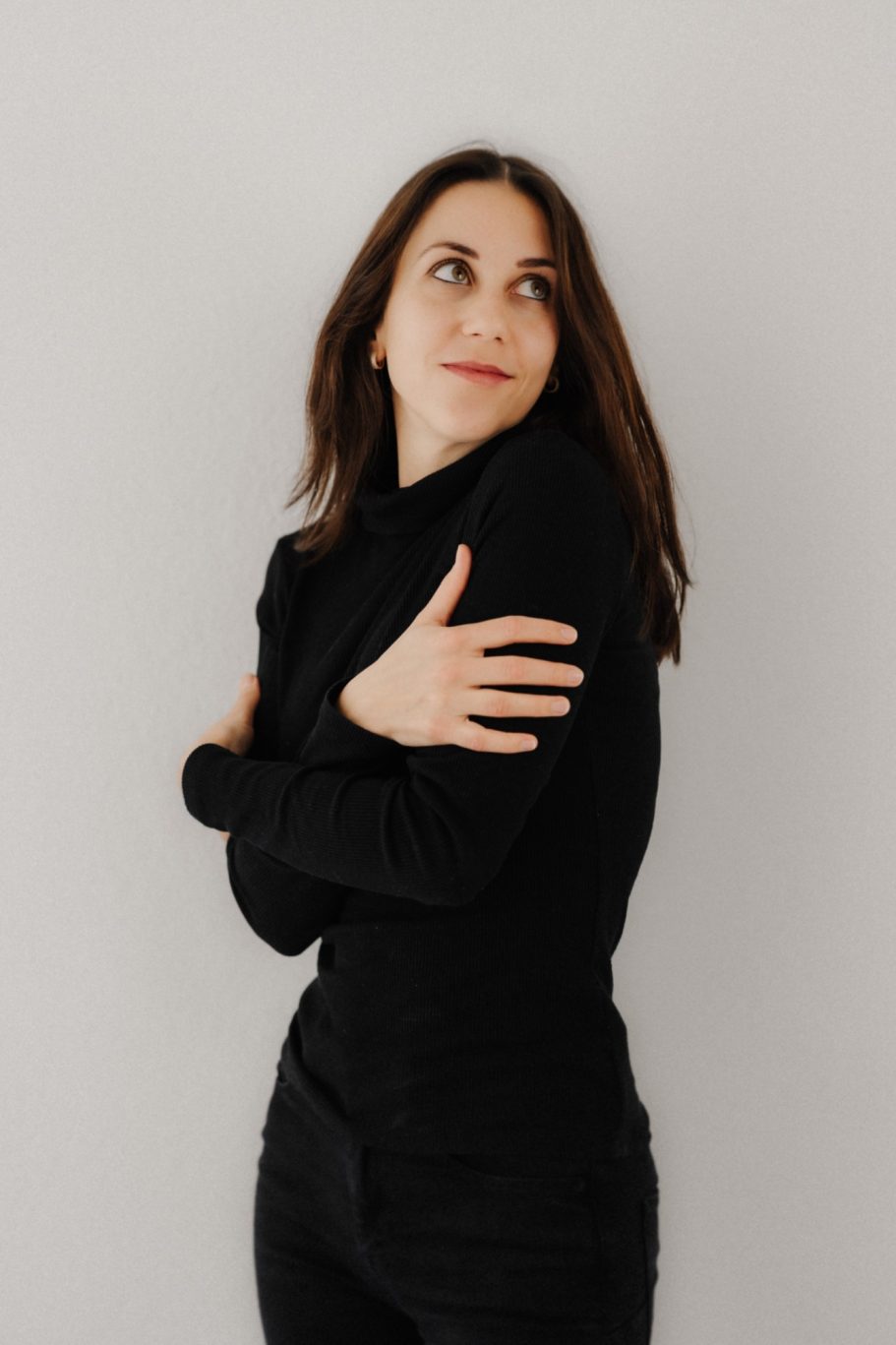 Junge Frau in schwarzem Oberteil, die nachdenklich in die Ferne blickt.