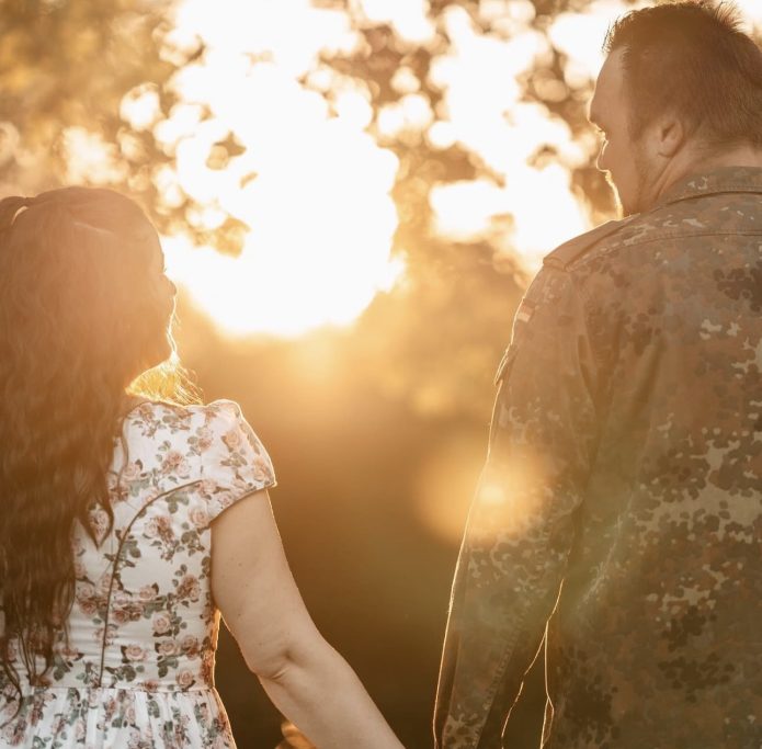Paar hält Händchen und blickt in die Sonnenuntergangsstimmung.